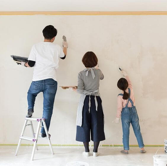 家族3人で壁を漆喰で塗っている写真